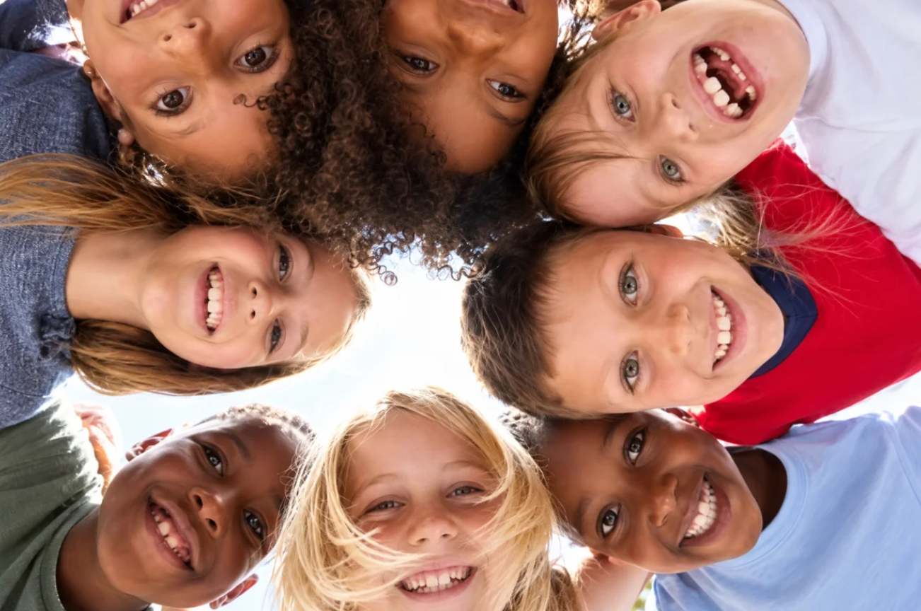 A circle of smiling children looking down at the camera
