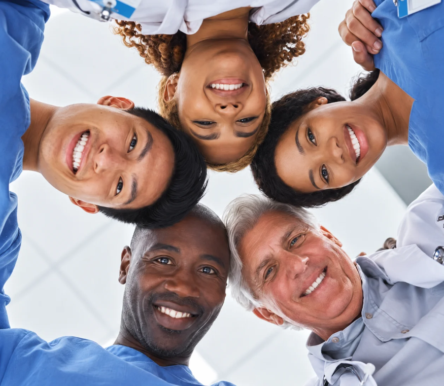 A group of smiling clinicians in a huddle, seen from below